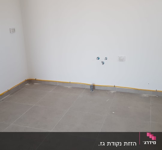 צינור גז צהוב מותקן לאורך הקיר בחדר ריק